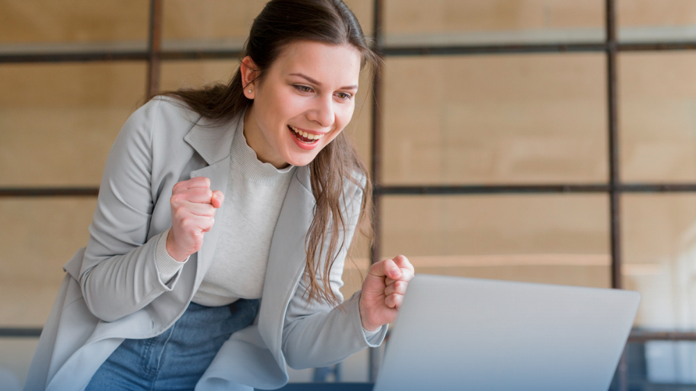Agente de seguros celebrando frente a su computadora al lograr control total de su cartera con CRM